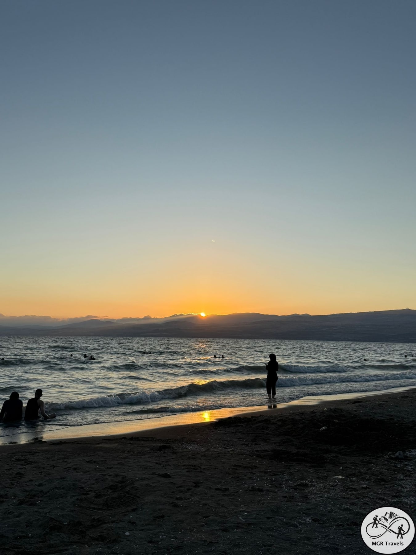 A silhouette by the water against a golden sunset